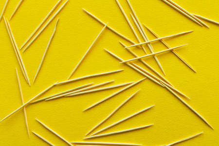 Lots of wooden toothpicks on a yellow background. The concept of order and chaosの写真素材