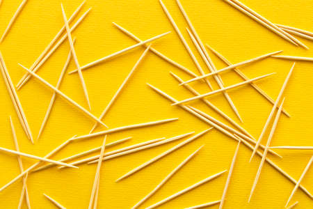 Lots of wooden toothpicks on a yellow background. The concept of order and chaosの写真素材