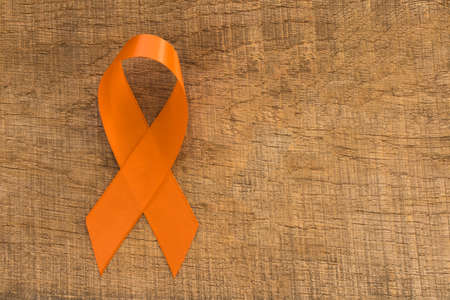 Orange ribbon on wooden background. Healthcare and medicine concept. Multiple Sclerosis awareness. Leukemia awareness. Empty text spaceの写真素材