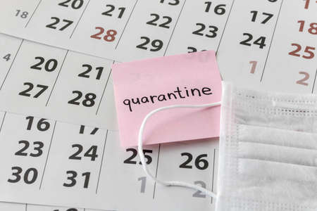 CORONAVIRUS. A sticker with the words quarantine and protective medical mask on the calendar sheets....