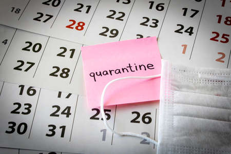 CORONAVIRUS. A sticker with the words quarantine and protective medical mask on the calendar sheets. The concept of quarantine. Selective focusの写真素材