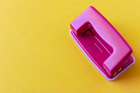 Pink hole punch on a yellow background. Close up