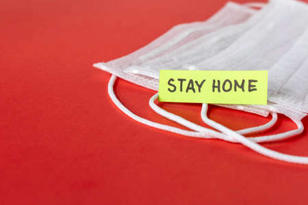 CORONAVIRUS. Protective medical mask, sticker with the word stay home on red background. The concept...