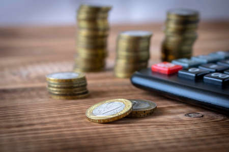 A stack of coins and a calculator on a wooden table. Concept of savings and financial accounting. Selective focusの写真素材