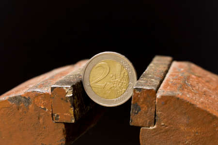 2 Euro coin in a metal vise. Concept of economic problems. Selective focus. Close upの写真素材
