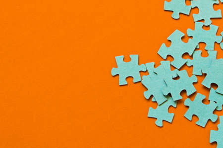 Puzzle. Many puzzle pieces on an orange background. The concept of collective thinking