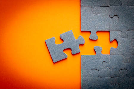 Puzzle. Many puzzle pieces on an orange background. The concept of collective thinking
