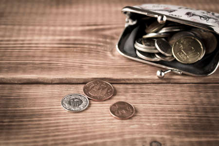 Wallet with coins on a wooden table. Close up. Selective focus. The concept of povertyの写真素材