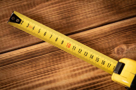 Yellow measuring tape on a wooden background. Close-upの写真素材