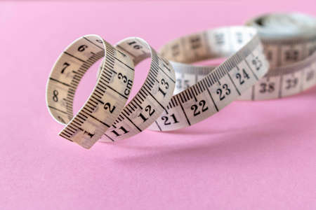 White measuring tape on a pink background. Close-upの写真素材