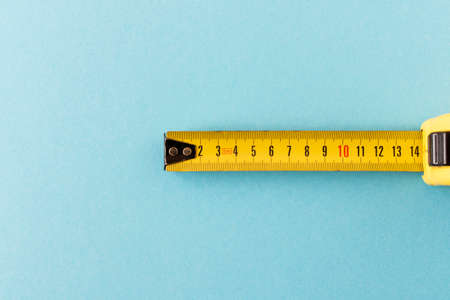 Yellow measuring tape on a blue background. Close-upの写真素材