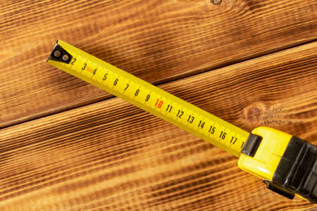 Yellow measuring tape on a wooden background. Close-upの写真素材