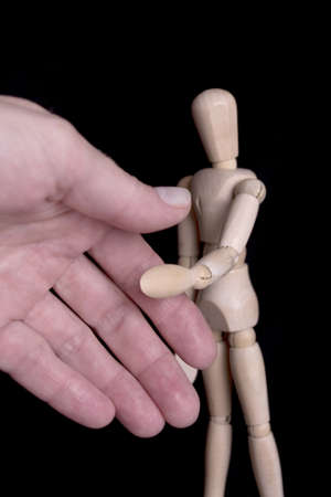 Wooden dummie shaking human hand over black backgroundの写真素材
