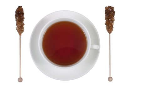 Brown amber sugar crystals on wood stick with a cup of teaの写真素材