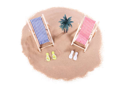 A small island with palm tree and two toy beach chairs over whiteの写真素材