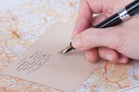 Female hand writing with old fountain pen a post cardの写真素材