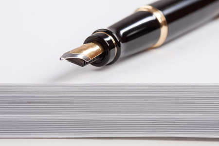 old fountain pen lying on a pile of paperの写真素材