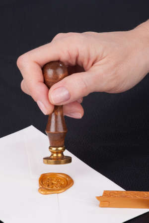 female hand stamps mail envelope with old gold wax seal stamps