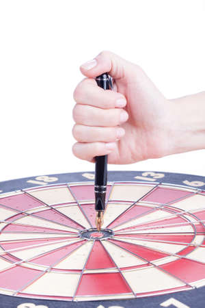 female hand sticks a Fountain pen in the target center dartboard over whiteの写真素材