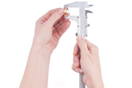 female hand measures the diameter of the wedding ring over white