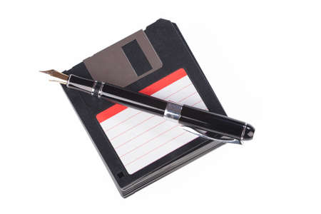 fountain pen lying on a pile of floppy disks over white