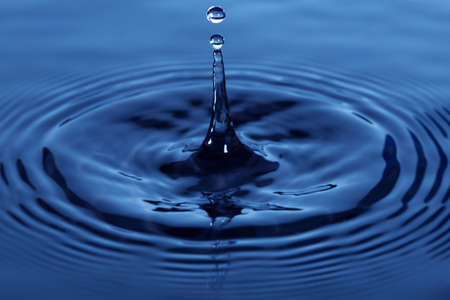 Splash drop of water on blue surfaceの写真素材