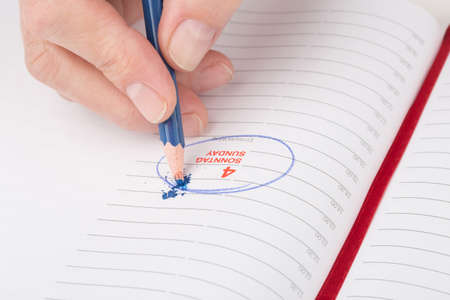 female hand breaks a lead pencil on a date in the calendarの写真素材