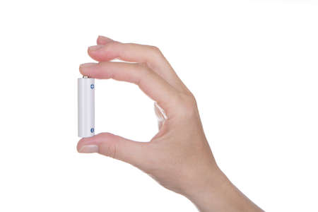 female hand holding a AA battery over white