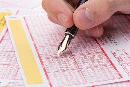 male hand filling fountain pen lotto ticketの写真素材
