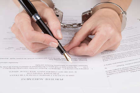 Female hands in handcuffs fill the contract on purchaseの写真素材