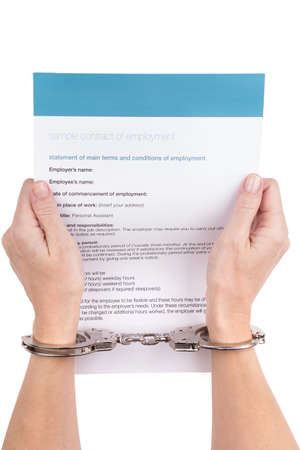 female hands in handcuffs holding the employment contractの写真素材
