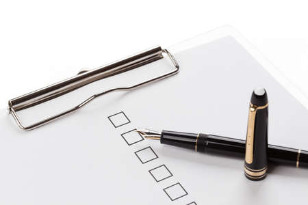 fountain pen and checkbox on the clip board over whiteの写真素材