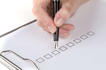 Female hand fills a document attached to the clipboard over white