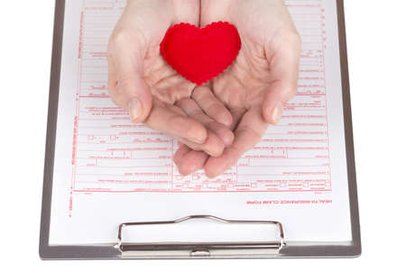 female hands holding a heart symbol over insurance claim form
