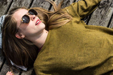 Woman wearing a sweater and lying on a wooden floorの写真素材