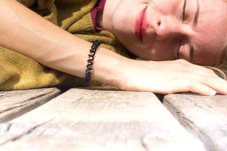 young woman sleeping outdoors on wooden floorの写真素材