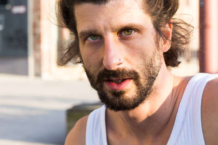 A hipster man with beard in tank top posing outdoorsの写真素材