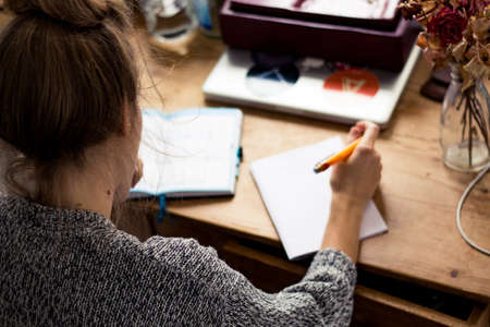 young woman writing a note in a paper bookの写真素材