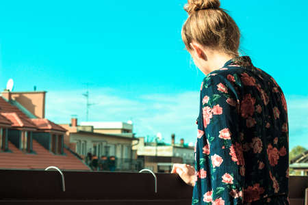 girl leaning on the railing and looking down from her balconyの写真素材