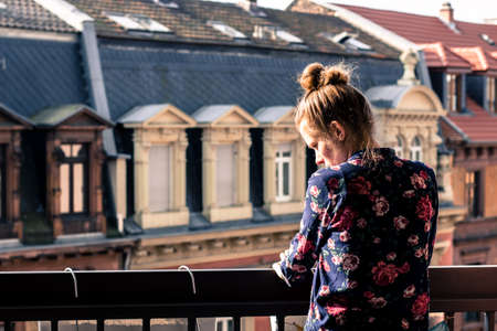 girl leaning on the railing and looking down from her balconyの写真素材