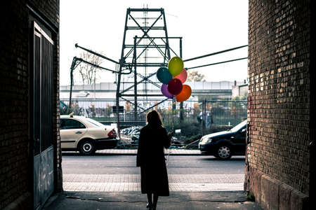 Woman walking in the city with colorful helium balloonsの写真素材