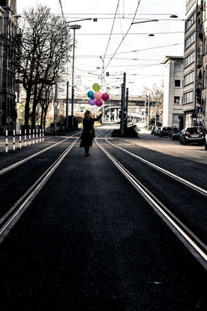 woman walking in the city with colorful helium balloons