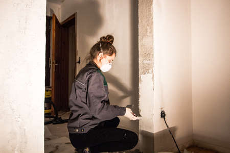 girl with dust mask plastering a door stock break throughの写真素材