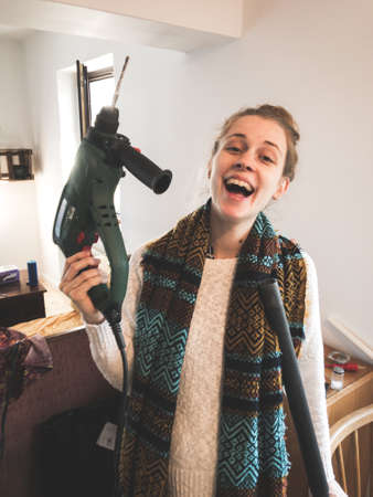 A woman holding a drilling machine while making home improvements and moving inの写真素材