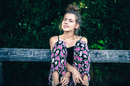 beautiful young woman sitting on a park bench in springの写真素材