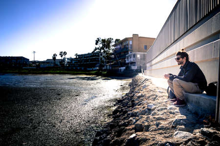 young man sitting at a scenic dried out lakeの写真素材