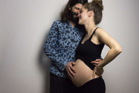 beautiful pregnant young woman and handsome boyfriend showing her belly