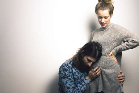 beautiful pregnant young woman and handsome boyfriend showing her belly