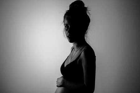 beautiful pregnant young woman posing in lingerie and showing her bellyの写真素材