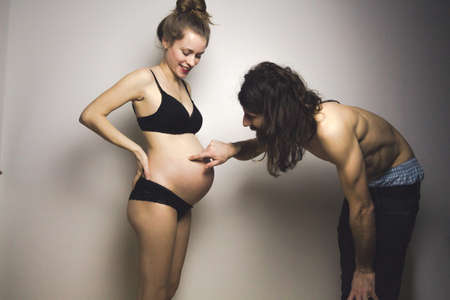 beautiful pregnant woman and her handsome boyfriend posing in lingerieの写真素材